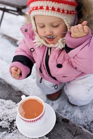 Small girl drinking cocoa from a spoon (out of doors) Stock Photo - Premium Royalty-Free, Code: 659-02212466