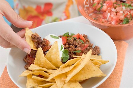 Hand dipping tortilla chip in mince sauce, salsa at side Stock Photo - Premium Royalty-Free, Code: 659-02212561