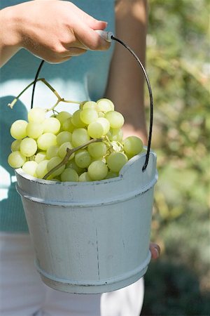 Woman holding green grapes in a wooden bucket Stock Photo - Premium Royalty-Free, Code: 659-02212627