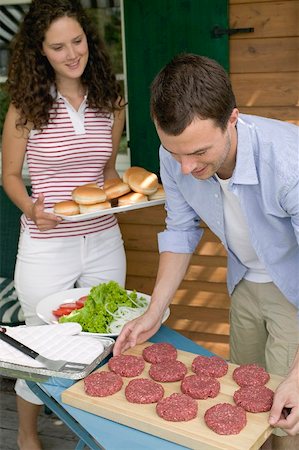 Man preparing burgers for grilling, woman bringing buns Stock Photo - Premium Royalty-Free, Code: 659-02212657