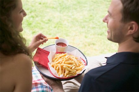 summer eating and clothes - Couple eating chips with ketchup in garden Stock Photo - Premium Royalty-Free, Code: 659-02212665