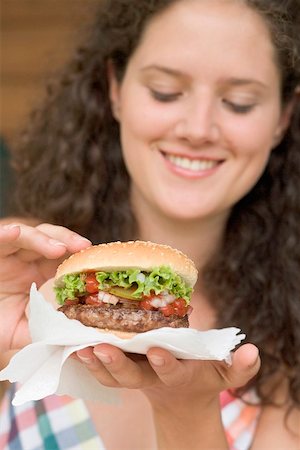 simsearch:659-02212700,k - Woman holding hamburger on paper napkin Foto de stock - Sin royalties Premium, Código: 659-02212697