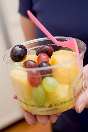 fruits in plastic cups - Woman holding plastic tub of fruit salad with fork Stock Photo - Premium Royalty-Free, Code: 659-02212753