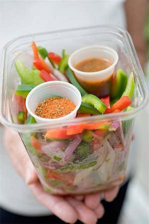 Woman holding plastic container of vegetables, seasonings & dip Stock Photo - Premium Royalty-Free, Code: 659-02212769