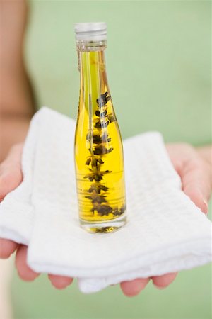 Woman holding bottle of body oil on towel Stock Photo - Premium Royalty-Free, Code: 659-02212873