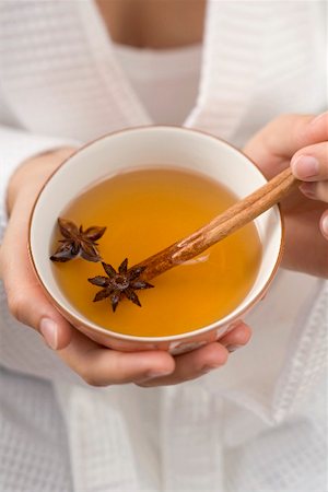 Woman holding bowl of tea with star anise & cinnamon stick Stock Photo - Premium Royalty-Free, Code: 659-02212937