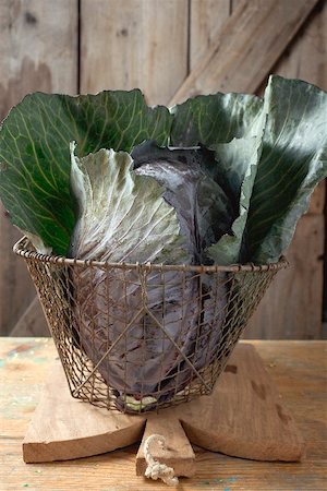 Red cabbage in basket on chopping board in front of wooden wall Stock Photo - Premium Royalty-Free, Code: 659-02212961