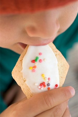 Child eating iced biscuit decorated with sprinkles Stock Photo - Premium Royalty-Free, Code: 659-02213009