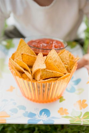 Child holding nachos and tomato salsa on tray Stock Photo - Premium Royalty-Free, Code: 659-02213069