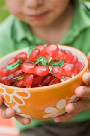 simsearch:659-01858229,k - Small boy holding bowl of cherry jelly sweets Fotografie stock - Premium Royalty-Free, Codice: 659-02213074