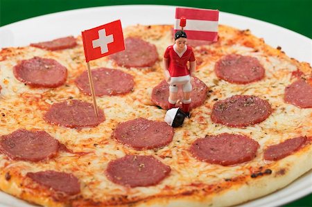 Salami pizza with toy footballer and two flags Stock Photo - Premium Royalty-Free, Code: 659-02213185