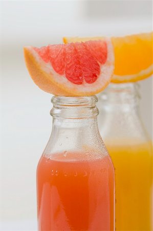 Three fruit juices in bottles with wedges of fresh fruit Stock Photo - Premium Royalty-Free, Code: 659-02213306