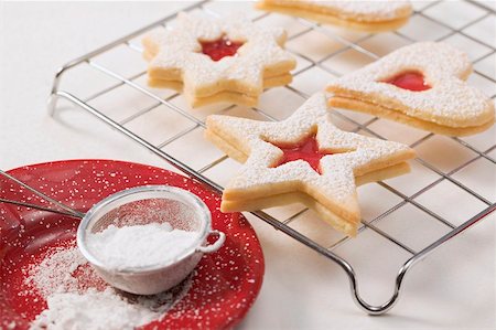 simsearch:659-02213379,k - Jam biscuits on cake rack, icing sugar in sieve Foto de stock - Royalty Free Premium, Número: 659-02213378