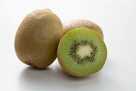 simsearch:659-02213458,k - Half a kiwi fruit in front of two whole kiwi fruits Foto de stock - Sin royalties Premium, Código: 659-02213450