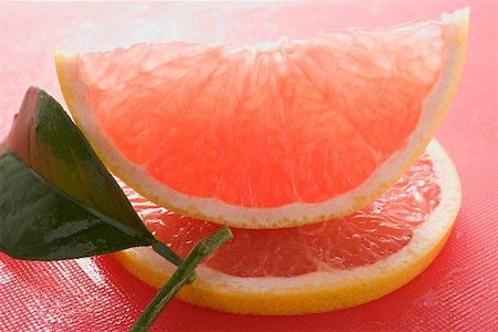 Wedge of pink grapefruit on slice of grapefruit with leaf Stock Photo - Premium Royalty-Free, Code: 659-02213474