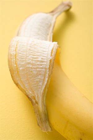 Banana, partly peeled, on yellow background Stock Photo - Premium Royalty-Free, Code: 659-02213470