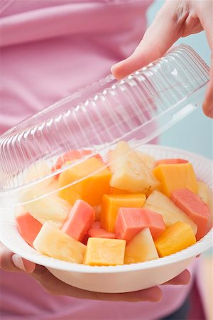 fruitsalad takeaway - Woman removing lid from plastic dish of exotic fruit salad Stock Photo - Premium Royalty-Free, Code: 659-02213551