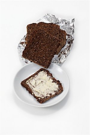 school packed lunch - Slices of black bread in foil, a slice buttered on plate Stock Photo - Premium Royalty-Free, Code: 659-02213903