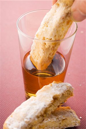 Hand dipping cantucci (Italian almond biscuit) into glass of Vin Santo Stock Photo - Premium Royalty-Free, Code: 659-03524245