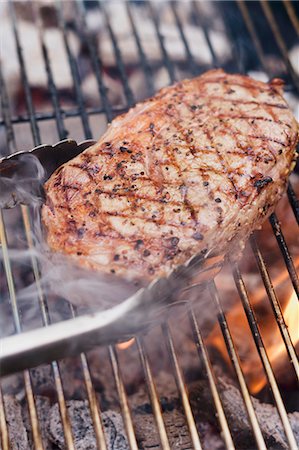 simsearch:659-03531168,k - Steak de boeuf sur le barbecue de fumer avec pinces à barbecue Photographie de stock - Premium Libres de Droits, Code: 659-03524285