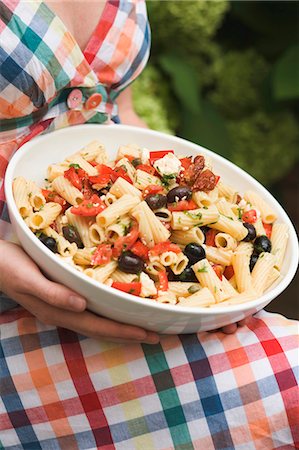 Woman holding a dish of pasta & vegetable salad on her knee Fotografie stock - Premium Royalty-Free, Codice: 659-03524286