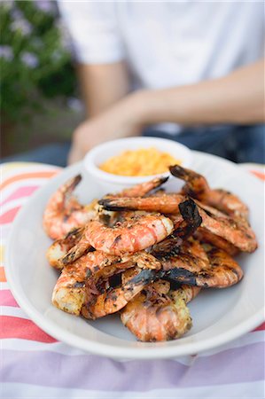 Grilled shrimps on plate, man in background Stock Photo - Premium Royalty-Free, Code: 659-03524315