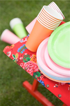 Coloured paper cups and plates on folding stool in garden Stock Photo - Premium Royalty-Free, Code: 659-03524323