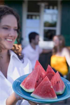 simsearch:659-02212726,k - Woman serving watermelon wedges, couple in background Foto de stock - Sin royalties Premium, Código: 659-03524364