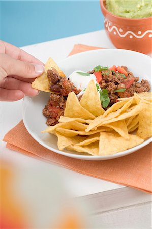 simsearch:659-08904862,k - Hand dipping tortilla chip in mince sauce Foto de stock - Sin royalties Premium, Código: 659-03524484
