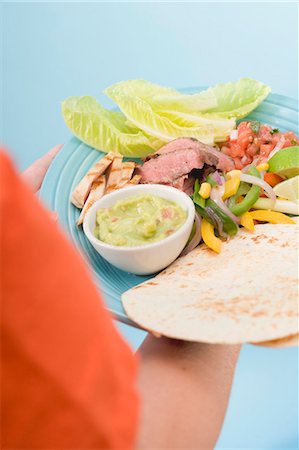 simsearch:659-06671664,k - Personne qui détient des fajitas et guacamole sur plaque Photographie de stock - Premium Libres de Droits, Code: 659-03524492