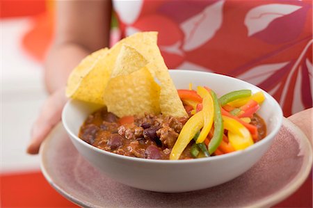 Woman serving chili con carne with nachos and peppers Stock Photo - Premium Royalty-Free, Code: 659-03524527