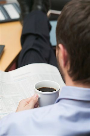 Businessman drinking coffee while reading newspaper in office Stock Photo - Premium Royalty-Free, Code: 659-03524561