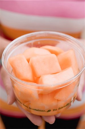 simsearch:659-02212753,k - Woman holding plastic tub of diced melon Stock Photo - Premium Royalty-Free, Code: 659-03524572