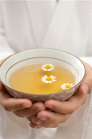 simsearch:659-06495759,k - Hands holding bowl of chamomile tea with flowers Foto de stock - Sin royalties Premium, Código: 659-03524633