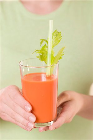 Woman holding glass of carrot juice with celery and straw Stock Photo - Premium Royalty-Free, Code: 659-03524664