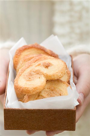 Hands holding palmiers (puff pastry biscuits) in box Stock Photo - Premium Royalty-Free, Code: 659-03525081