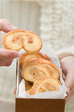 Hand taking palmier (puff pastry biscuit) from box Stock Photo - Premium Royalty-Free, Code: 659-03525082