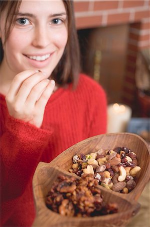 Young woman eating nuts in front of fireplace (Christmas) Stock Photo - Premium Royalty-Free, Code: 659-03525105
