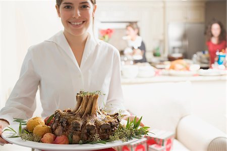 people holding food platters - Young woman serving rack of pork for Christmas Stock Photo - Premium Royalty-Free, Code: 659-03525118