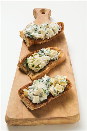 Artichokes and basil on toast on chopping board Stock Photo - Premium Royalty-Free, Code: 659-03525182