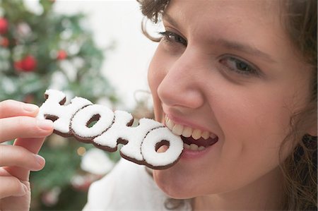 person food label - Woman biting Christmas biscuit (the word HOHO) Stock Photo - Premium Royalty-Free, Code: 659-03525273