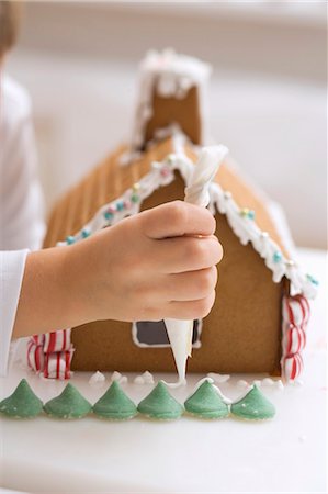 decorating - Child decorating gingerbread house with piping bag Stock Photo - Premium Royalty-Free, Code: 659-03525425