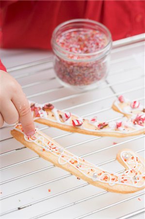 dredging sugar - Child decorating Christmas biscuits with sprinkles Stock Photo - Premium Royalty-Free, Code: 659-03525442