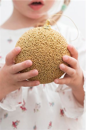 simsearch:659-03529405,k - Small girl holding gold Christmas bauble Fotografie stock - Premium Royalty-Free, Codice: 659-03525458