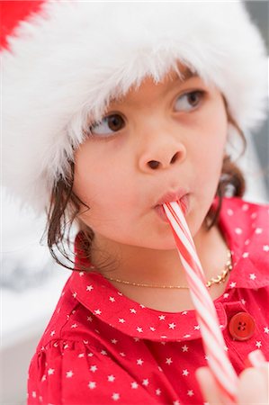 simsearch:659-06153344,k - Small girl in Father Christmas hat eating candy cane Foto de stock - Sin royalties Premium, Código: 659-03525786