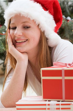 simsearch:659-03526806,k - Femme au chapeau de père Noël regardant des colis de Noël Photographie de stock - Premium Libres de Droits, Code: 659-03525853