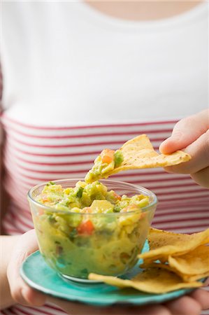 Woman dipping tortilla chip in guacamole Stock Photo - Premium Royalty-Free, Code: 659-03526514