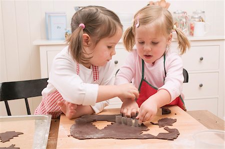 Two small girls cutting out chocolate biscuits Foto de stock - Sin royalties Premium, Código: 659-03526636