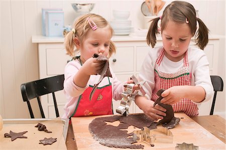 Two small girls cutting out chocolate biscuits Stock Photo - Premium Royalty-Free, Code: 659-03526631