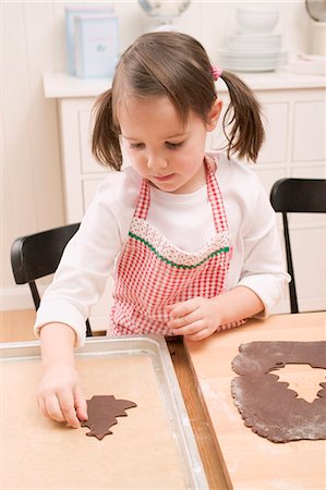 simsearch:659-03525780,k - Small girl placing chocolate biscuit on baking tray Foto de stock - Sin royalties Premium, Código: 659-03526633